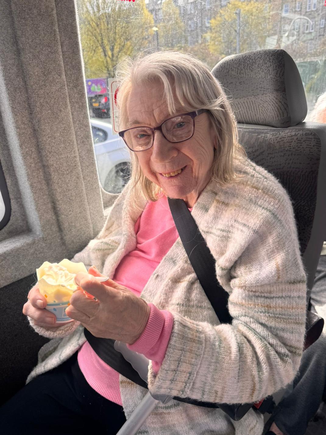 resident smiling in the minibus eating an ice cream