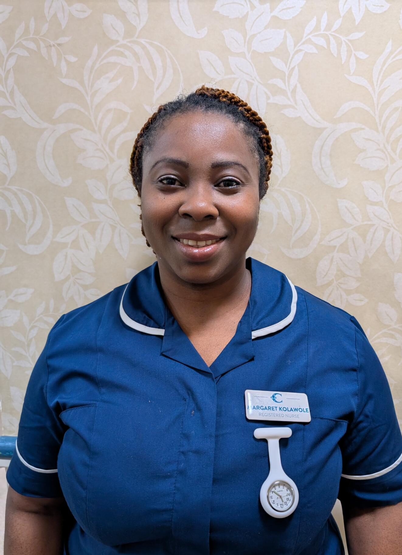 a female nurse smiling in a dark blue uniform