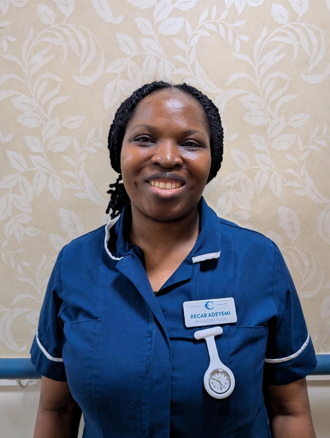 a woman smiling in a dark blue nurses uniform