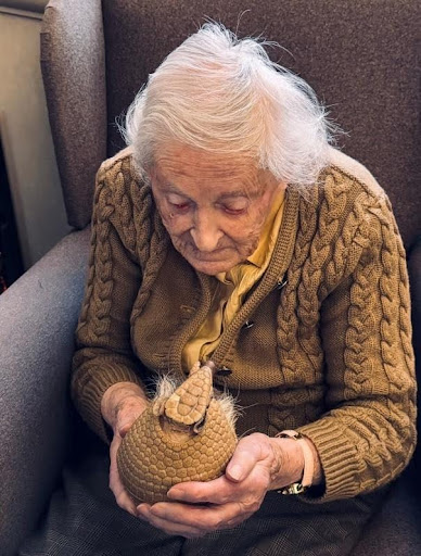 elderly woman in a care home holding an armadillo