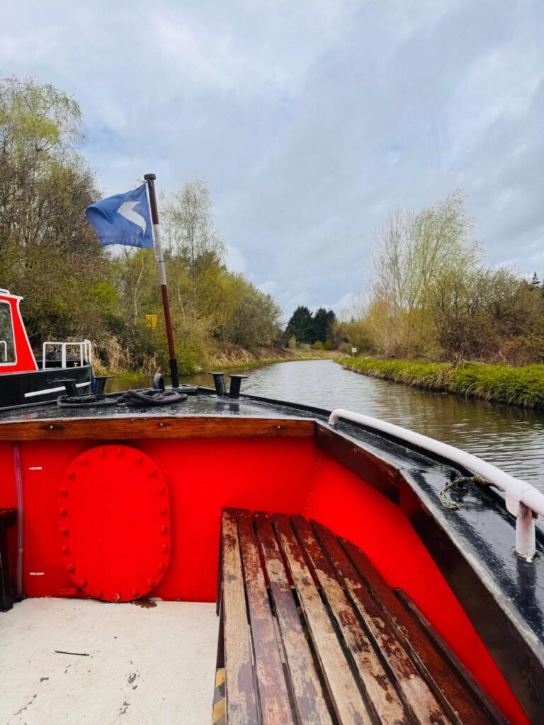 the front of a red canal boat on the water