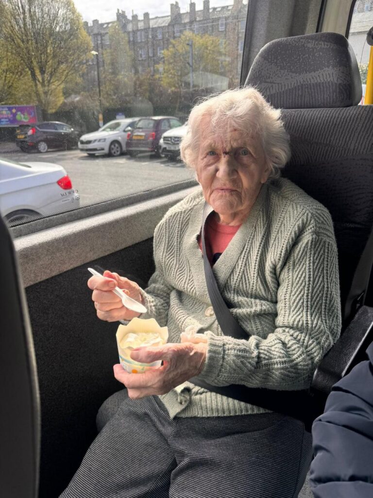 elderly woman enjoying an ice cream on a minibus