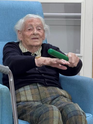 elderly woman with arms out stretched in an exercise activity